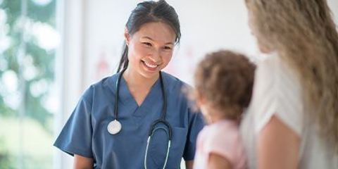 Female doctor smiles at a child patient and her mother